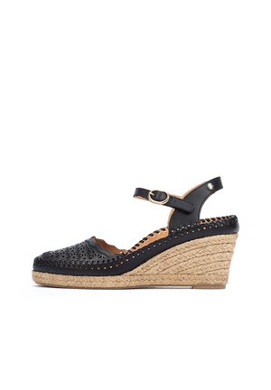 Sandalia de cuña de cuero negro con diseño de cortes, tacón cubierto de yute, correa ajustable y superficie texturizada.