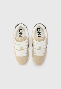 Beige sneakers med hvite snøringer, myk semsket tekstur, svart hæl, og "ONLY" logo på tungen og innersålen.