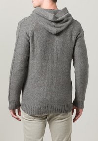 Szary dzianinowy sweter z kapturem, teksturowanej tkaniny, z prążkowanym dołem i bocznymi warkoczowymi detalami. Wykończony w jednolitym kolorze z nakrapianymi akcentami.