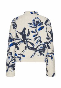 Quilted jacket with a cream background, featuring a blue floral pattern. Long sleeves and a collar finish the design.