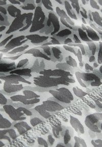Grijze stof met een zwart leoprintpatroon. Het materiaal heeft een gladde textuur, met gestikte details langs de rand.