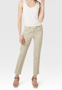 Beiga byxor med rak passform, gjorda av lättviktig tyg, med fickor framtill. Kombinerat med en vit linne och espadrillosandaler.