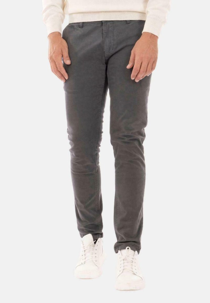Pantaloni grigi slim-fit in cotone. Presentano un design pulito, tasche frontali e passanti per la cintura. Abbinati a sneakers bianche.