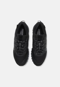 Czarne buty sportowe z teksturowanej tkaniny, wzmocnioną osłoną palców i gumową podeszwą. Zawierają system sznurowania oraz oddychającą siateczkę.