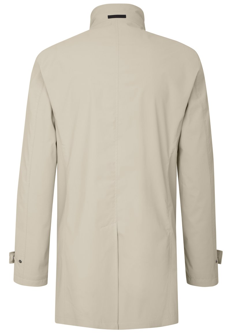 Manteau long beige avec un col haut, présentant une texture lisse, une coupe droite et des poignets boutonnés. Design minimaliste, sans fermetures visibles.