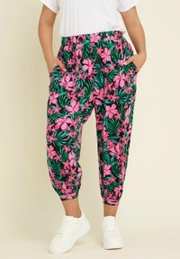Joggingbyxor med blommönster som har rosa blommor och gröna blad på en mörk bakgrund, med elastisk midja och sidofickor.