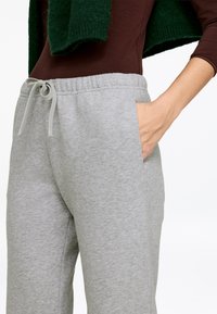 Grey sweatpants with an elastic waistband, adjustable drawstring, and side pockets. Fabric has a soft, textured finish.