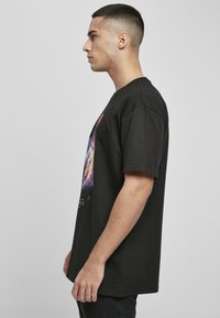 Sort bomulds T-shirt med et farverigt grafisk print på forsiden. Løs pasform, korte ærmer, rund halsudskæring og flad kant.