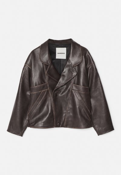 Rudas odinė striukė su įpjautu apykakle, asimetrišku mygtukų uždarymu ir ryškiai matomais šoniniais kišenėmis. Turtinga kontrastinga siuvinėjimo detalė.