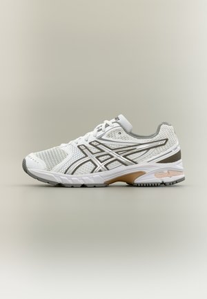 Hvite sportssko med mesh-overside, grå aksenter og en polstret såle. Har et mønstret design og forsterket tåhette.