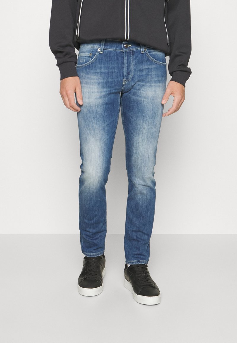 Světle modré džíny s úzkým střihem, se zašlým umytím, pětiokou kapsou a jemnými efekty nažehlení. Nosit s černými teniskami.