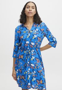 Rochie florală albastră cu închidere cu nasturi în față, mâneci trei sferturi și curea legată. Prezintă modele colorate de flori pe un material moale.