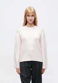 Ροζ ανοιχτό πουλόβερ με υφή, στρογγυλή λαιμόκοψη και μακριά μανίκια. Διακοσμητικές ραφές κατά μήκος του τελειώματος και των μανσετών.