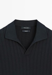 Schwarzes, geripptes Baumwoll-Poloshirt mit Hemdkragen, etikettiert mit Massimo Dutti, hergestellt in China.