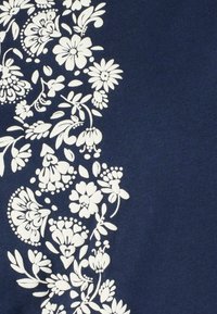 Tejido azul marino con estampado floral blanco que presenta varias flores y hojas, dispuestas a lo largo de un lado en un patrón detallado e intrincado.