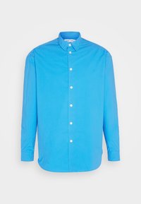 Chemise bleu vif à manches longues avec col pointu et boutons blancs, présentée sur un fond blanc uni.