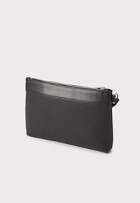 Sac à main noir avec une surface texturée, comportant des accents en cuir lisse, une fermeture éclair et une bandeau pour le poignet. Forme rectangulaire.