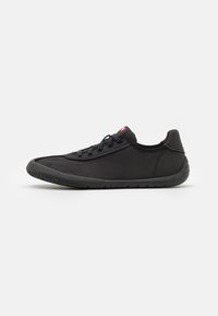 Black athletic shoe with a smooth textile upper, textured rubber sole, and flat laces. Features a low profile and rounded toe design.
