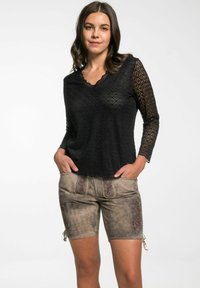 Zwarte kanten top met lange mouwen en een scalloped halslijn, gecombineerd met bruine shorts met geborduurde bloemenaccenten.