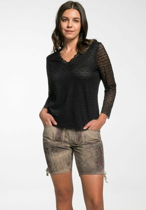 Schwarzes Spitzentop mit langen Ärmeln und einem gewellten Ausschnitt, kombiniert mit braunen Shorts mit bestickten Blumenakzenten.