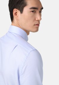 Lichtblauwe overhemd met een gestructureerde kraag, voorzien van een textuurpatroon. Het overhemd is op maat gemaakt met een getailleerde silhoët en nette naden.