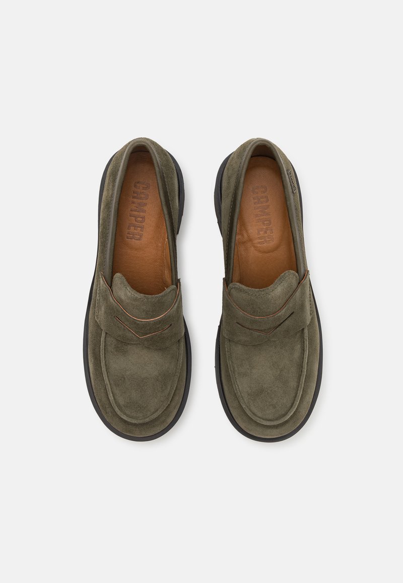 Scarpe slip-on in suede verde con rivestimento in pelle marrone e suola in gomma nera, caratterizzate da dettagli cuciti e una punta rotonda.