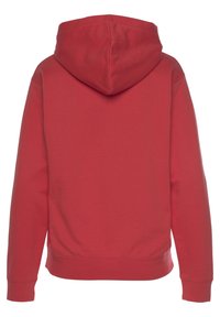 Punainen huppari, jossa on tilava huppu, pitkät hihat ja ribbaushelma. Materiaali on pehmeä, sileä ja ilman lisäkuvioita tai yksityiskohtia.