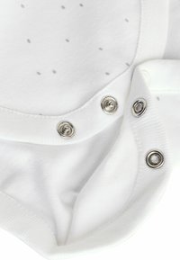 Weißer Body mit grauen Polka-Dots. Verfügt über Druckknopfverschlüsse und eine weiche Baumwolltextur. Runde Ausschnittform und sanfte Stichdetails.