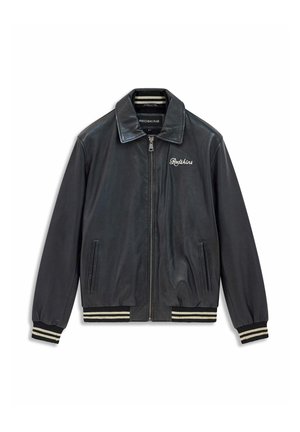 Veste aviateur en cuir noir avec fermeture éclair, poignets et ourlet côtelés ornés de rayures blanches, et le mot "Redskins" brodé sur la poitrine.