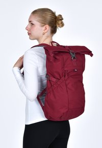 Zaino color bordeaux con design a roll-top, tasche laterali, spallacci regolabili e dettagli grigi. Realizzato in tessuto resistente, adatto per l'uso quotidiano.