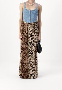 Denim bodice dengan ritsleting depan, bertransisi ke rok panjang dengan pola leopard. Rok tersebut lembut, menampilkan bintik-bintik cokelat dan hitam di latar belakang krem.