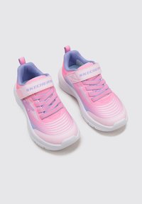 Zapatillas ligeras en tonos rosa y lavanda con parte superior texturizada, suela blanca y correa de Velcro. Presenta el logotipo distintivo en la correa y en el lateral.