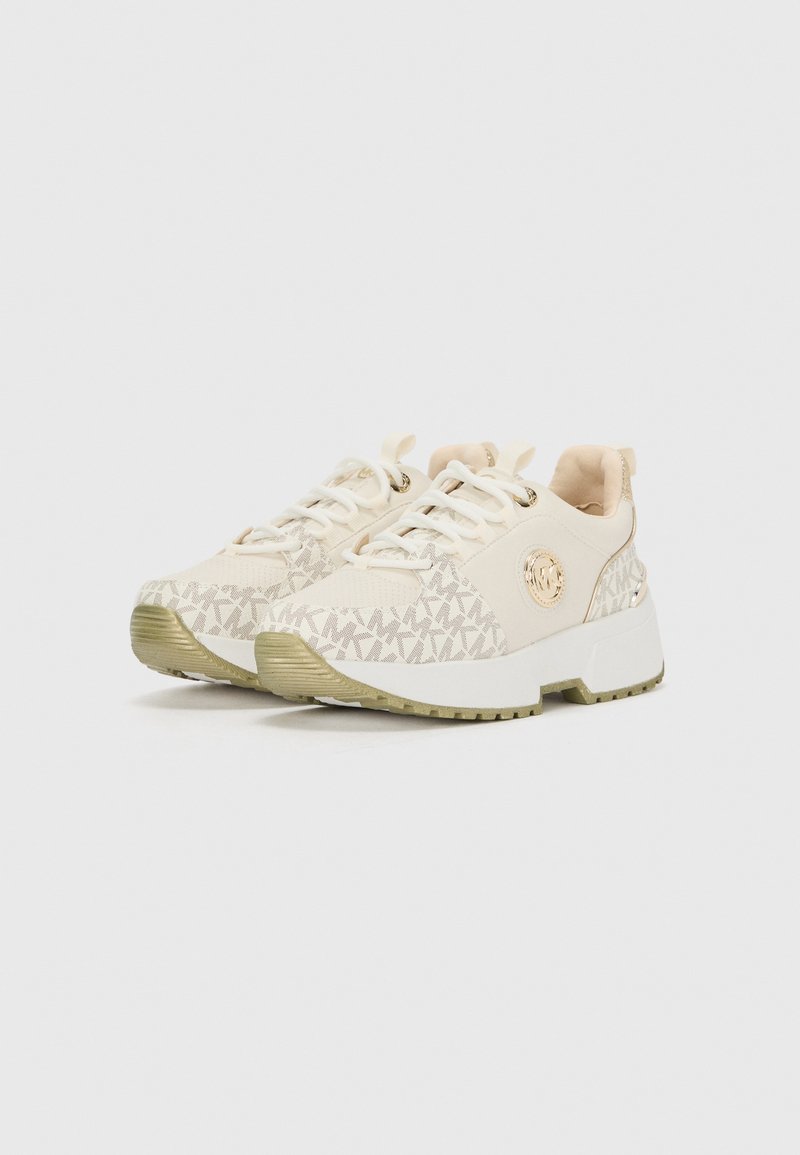 Baskets beiges avec une partie supérieure à motifs, semelles blanches et détails texturés. Elles présentent un design à lacets et un accent logo sur le côté.