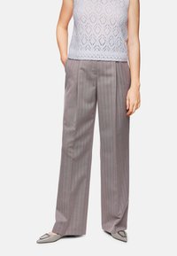 Light gray knit top with a diamond pattern, paired with wide-legged gray striped trousers and pointed-toe gray shoes with a decorative buckle.