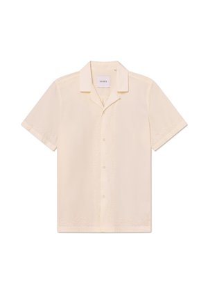 Chemise beige clair à manches courtes avec un motif brodé subtil le long des boutons et des manches, fabriquée en tissu léger.