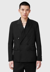 Blazer nero doppiopetto realizzato in tessuto liscio, con revers a pettine, due tasche frontali e dettagli con bottoni. Vestibilità su misura.