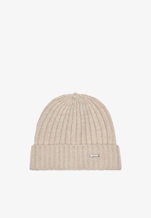 Gorro de punto beige con patrones de costilla vertical, con un puño doblado y una pequeña etiqueta metálica en el lateral. Textura suave.