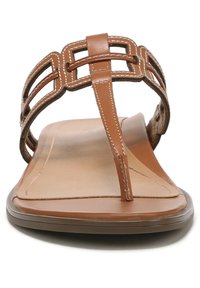 Brown leather thong sandals with a geometric strap design, flat sole, and minimal stitching detail. Smooth texture, open-toe style.