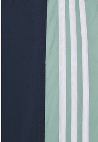 Námořnická modrá a mátově zelená látka se třemi bílými pruhy. Hladký povrch s viditelným švem podél okrajů.