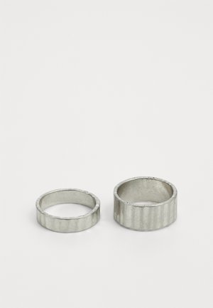 Sølvringer, en med en glatt ring og den andre med en rillede overflate. Begge har en polert finish og runde former.