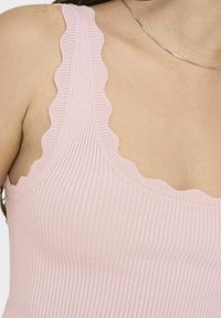 Top sin mangas de rayas en rosa claro con bordes con volantes en los tirantes y el escote, textura suave, diseño ajustado, construcción sin costuras.