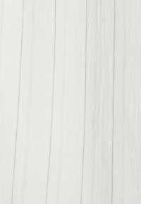 Tejido textil en blanco claro con pliegues verticales, que presenta una superficie suave y texturada con un tenue brillo. Diseño liso y fluido.