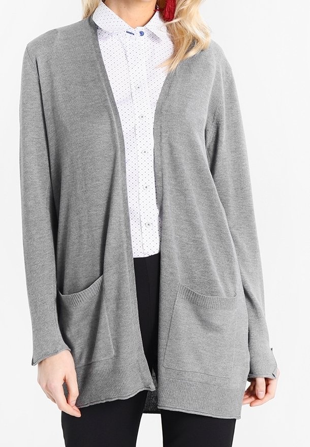 Cardigan gris à ouverture avant en tissu doux, avec deux poches frontales, poignets côtelés et coupe décontractée, superposé à une chemise à pois.