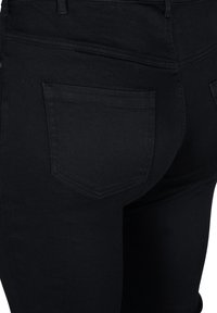 Black stretch jeans with a fitted design, featuring a subtle texture, two back pockets, and tonal stitching for a cohesive look.