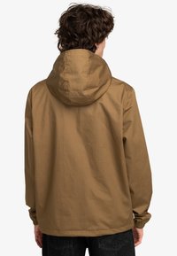 Chaqueta con capucha marrón de corte relajado, que presenta una superficie texturizada, puños elásticos y un diseño simple y aerodinámico.
