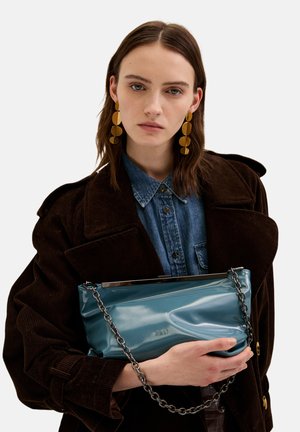Clutch in pelle verniciata color turchese con tracolla a catena, caratterizzato da una texture liscia e un design leggermente accartocciato. Finiture metalliche sulla parte superiore.