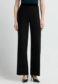 Zwarte wijde broek met een gladde textuur, voorzien van een fluwelen tailleband. Getailleerde pasvorm met voorplooien en een scherpe afwerking.