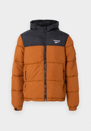 Pružná bunda s čiernou hornou časťou a oranžovou dolnou časťou, so zipsom vpredu, nastaviteľnou kapucňou a logom Reebok na hrudi.