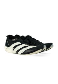 Un paio di scarpe atletiche nere con strisce bianche a pennellate, lacci neri e suola testurizzata, esposte affiancate su uno sfondo bianco.