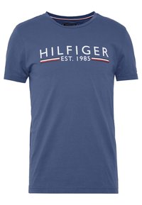 T-shirt in cotone blu a maniche corte con la scritta bianca "HILFIGER" e strisce rosse e bianche. Classico colletto girocollo, texture liscia, vestibilità casual.